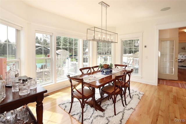 dining area with an inviting chandelier, baseboards, plenty of natural light, and light wood finished floors