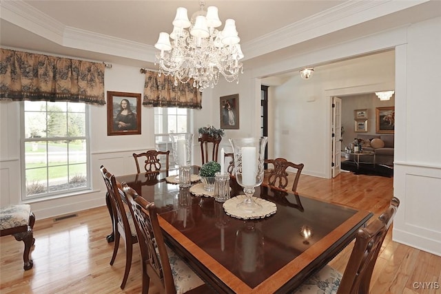 dining area featuring light wood-style floors, crown molding, an inviting chandelier, and visible vents