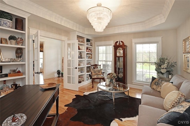interior space with french doors, wood finished floors, a tray ceiling, and an inviting chandelier