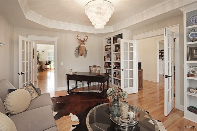 living area with an inviting chandelier, ornamental molding, french doors, and wood finished floors