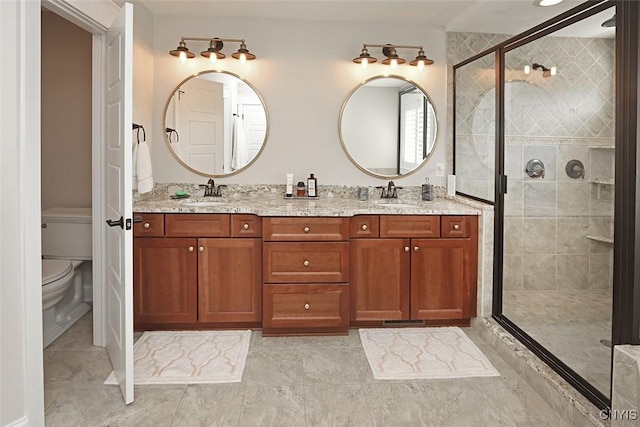 bathroom featuring a sink, a stall shower, toilet, and double vanity
