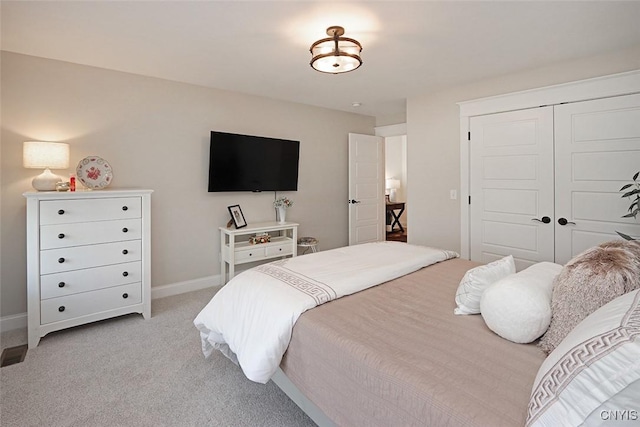 bedroom featuring light colored carpet, baseboards, and a closet