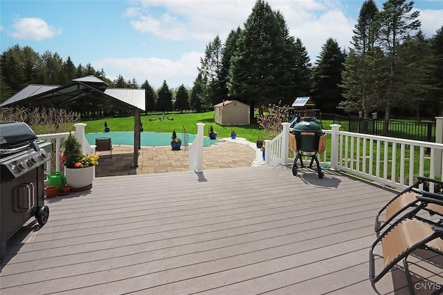 wooden deck featuring a storage unit, area for grilling, a patio area, a lawn, and an outdoor structure