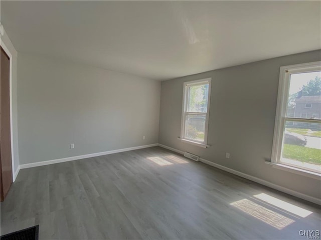 empty room with baseboards, visible vents, and a healthy amount of sunlight