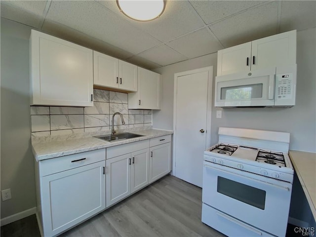 kitchen featuring a sink, white cabinetry, a drop ceiling, and white appliances