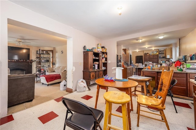 dining room with a fireplace, a ceiling fan, and light floors