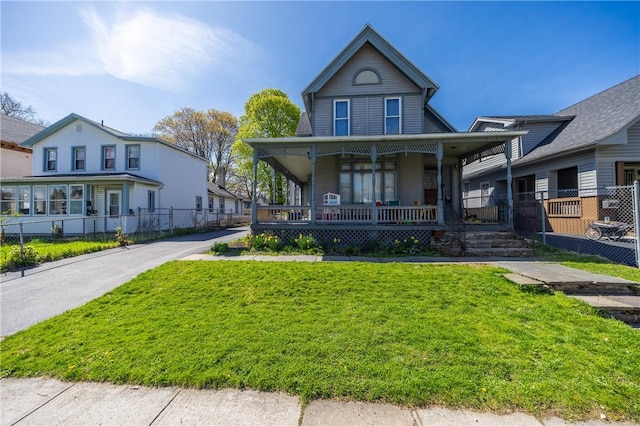 view of front of house with covered porch, fence, and a front lawn