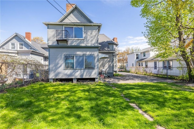 rear view of house with a lawn, fence, and a chimney