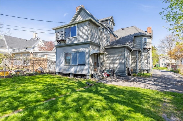 rear view of property featuring a yard, a chimney, and entry steps