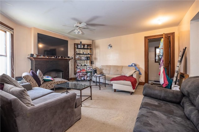carpeted living area featuring a ceiling fan and a fireplace