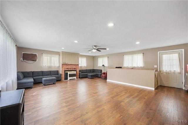living room featuring ceiling fan, a brick fireplace, recessed lighting, baseboards, and wood finished floors