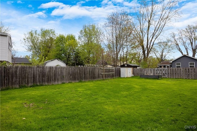 view of yard featuring a storage unit, a fenced backyard, and an outdoor structure