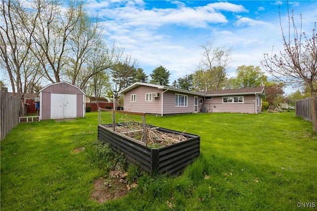 rear view of property featuring a fenced backyard, a storage unit, a yard, and a vegetable garden