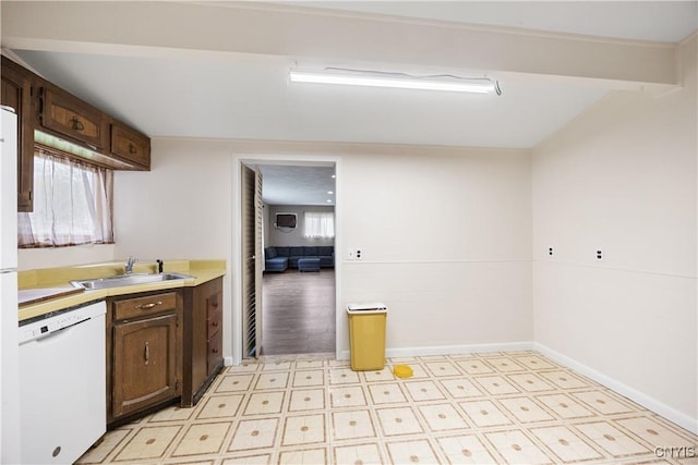 kitchen with dark brown cabinets, a sink, dishwasher, light countertops, and light floors