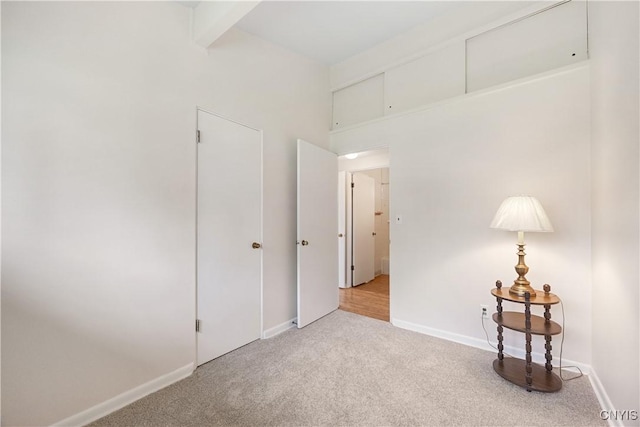 carpeted spare room featuring baseboards and beam ceiling