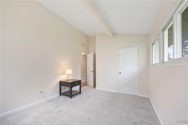 unfurnished bedroom featuring baseboards, lofted ceiling with beams, and light colored carpet