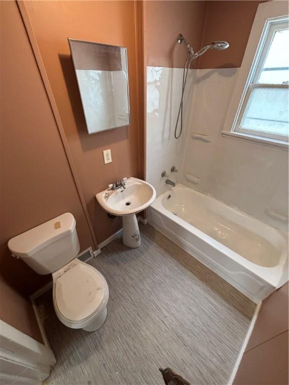 bathroom with shower / bathtub combination, toilet, and a sink