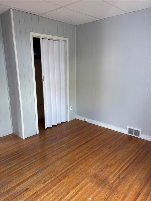 unfurnished bedroom with baseboards, visible vents, wood finished floors, and a closet