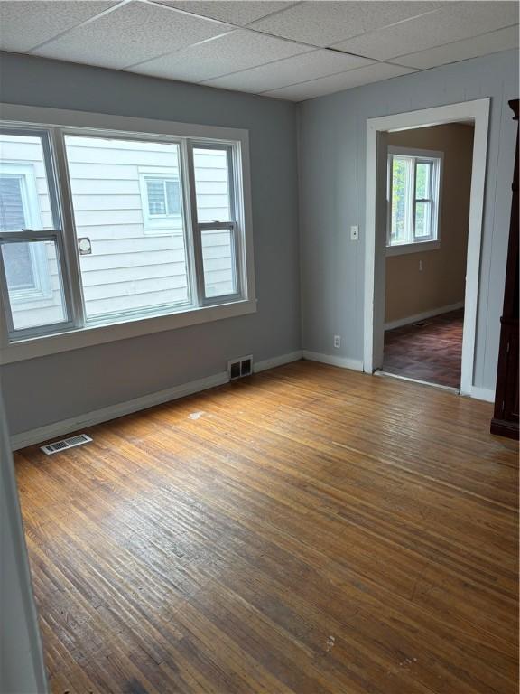 unfurnished room featuring visible vents, baseboards, and wood finished floors