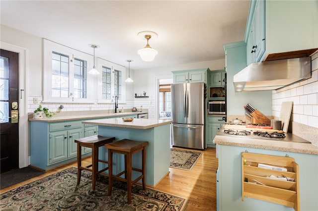 43 S Main St, Elba, NY 14058 - kitchen featuring appliances with stainless steel finishes, under cabinet range hood, green cabinets, decorative backsplash, and light countertops