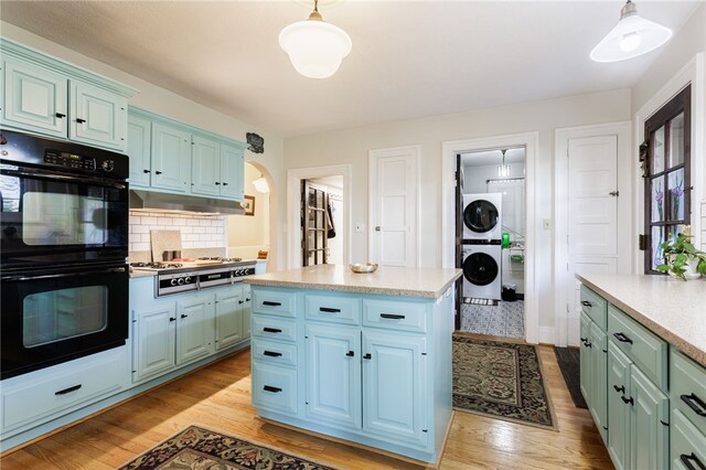 43 S Main St, Elba, NY 14058 - kitchen featuring stacked washer and clothes dryer, light countertops, light wood-style floors, and hanging light fixtures