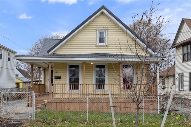 bungalow with a gate, covered porch, a fenced front yard, and metal roof