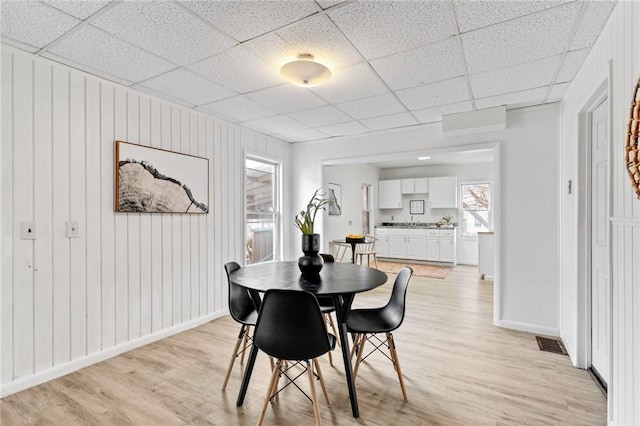 dining space with light wood-style floors, baseboards, a paneled ceiling, and visible vents