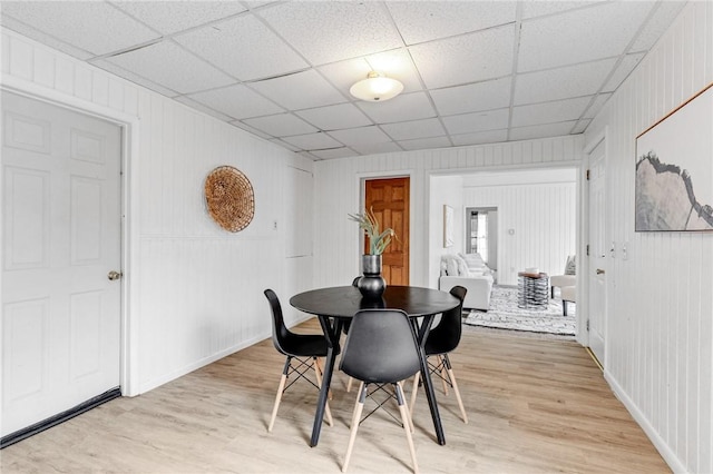 dining area with baseboards, light wood-style flooring, and a paneled ceiling