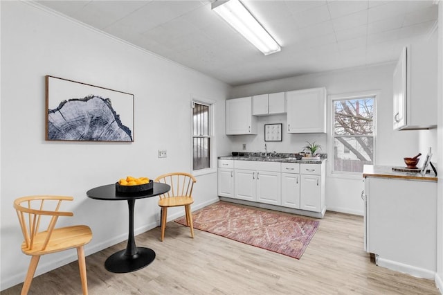 kitchen with white cabinets, plenty of natural light, a sink, and light wood-type flooring
