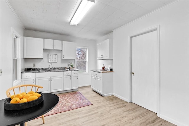 kitchen with ornamental molding, light wood-style flooring, and white cabinetry