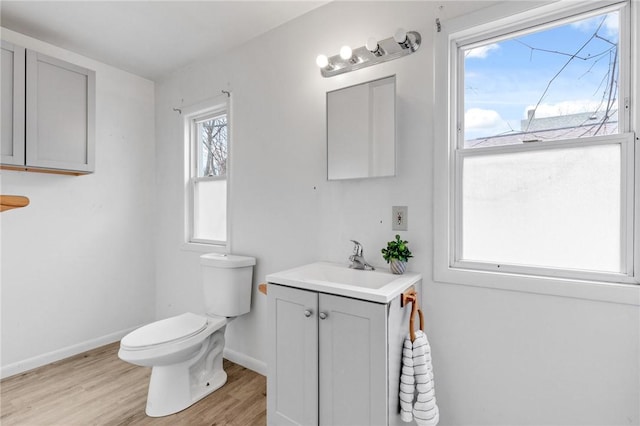 half bathroom with baseboards, wood finished floors, toilet, and vanity