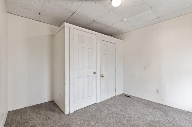 unfurnished bedroom featuring carpet and a drop ceiling