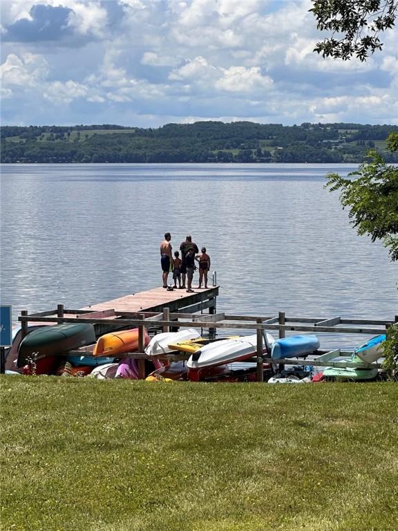 view of dock with a water view and a yard