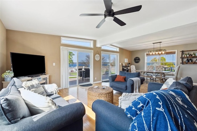 living area with baseboards, a ceiling fan, lofted ceiling with beams, and wood finished floors