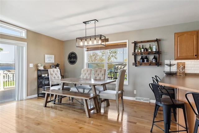 dining area with light wood-style floors, plenty of natural light, and visible vents