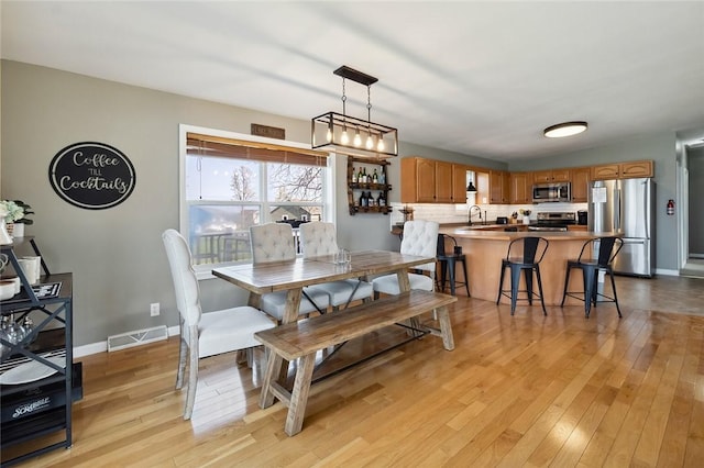 dining space featuring baseboards, light wood-type flooring, and visible vents