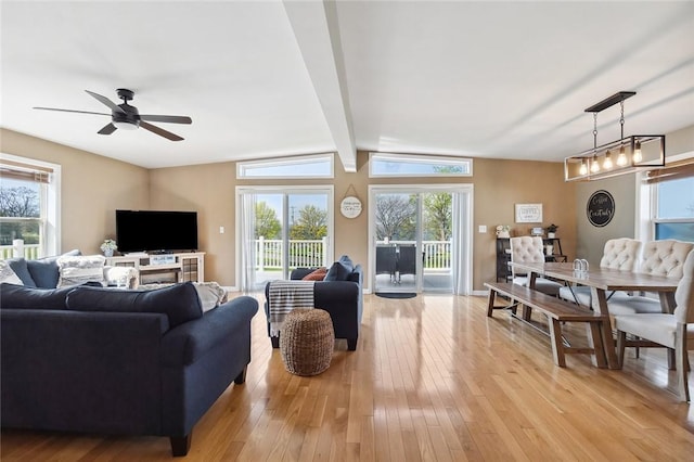 living area featuring light wood-type flooring, a wealth of natural light, and vaulted ceiling with beams