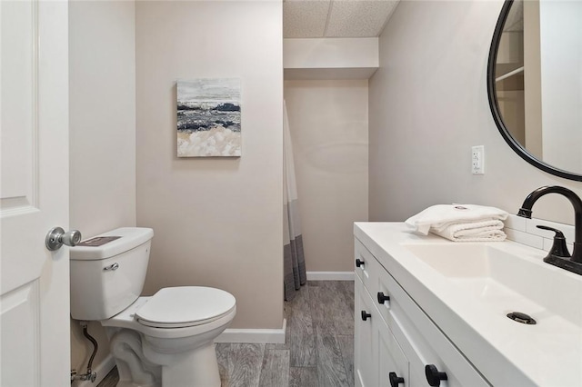 bathroom with vanity, baseboards, wood finished floors, and toilet