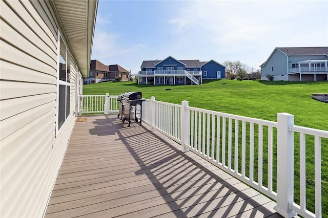 wooden deck with a yard, a residential view, and a grill