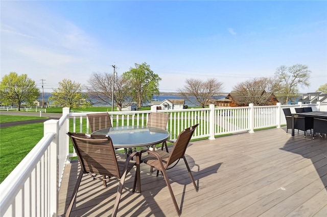 deck featuring outdoor dining area and a lawn