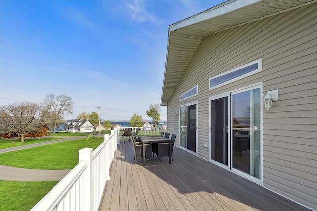 wooden terrace featuring outdoor dining area and a yard