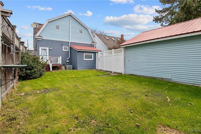 back of property featuring a lawn, a fenced backyard, and metal roof