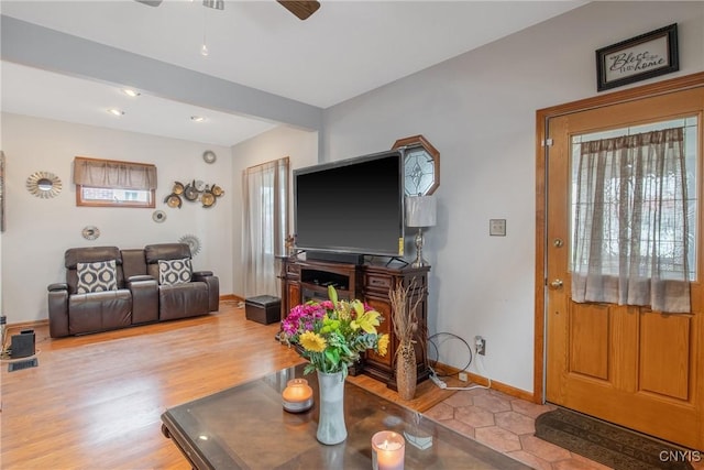 living area with baseboards, ceiling fan, and wood finished floors
