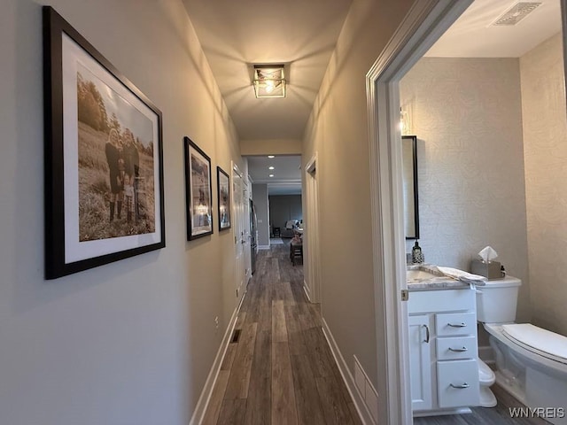 corridor with baseboards, visible vents, and dark wood finished floors