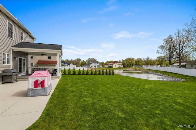 view of yard with a patio area, a water view, fence, and ceiling fan