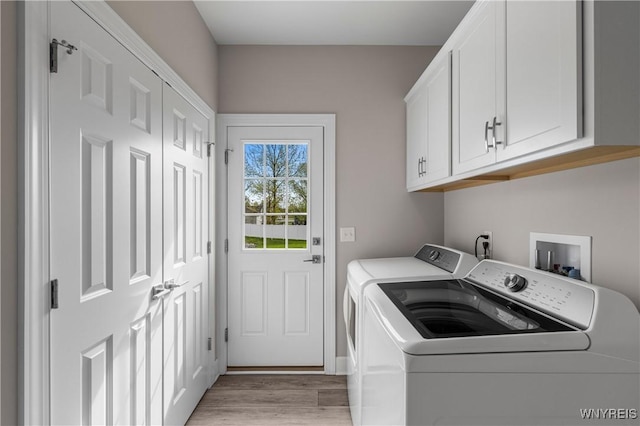 laundry room with washer and dryer, cabinet space, and light wood-style floors