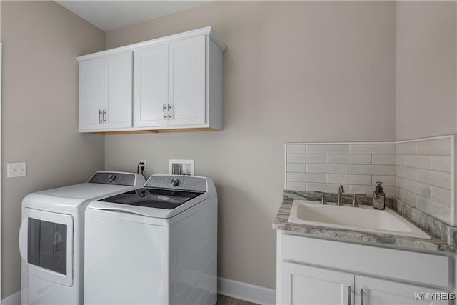 laundry area featuring washing machine and dryer, cabinet space, and baseboards