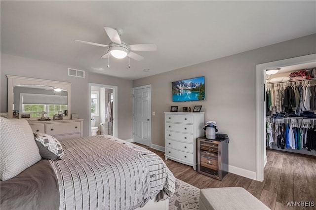 bedroom with wood finished floors, a closet, a walk in closet, visible vents, and baseboards