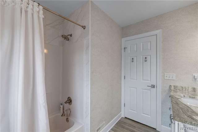 full bath with shower / bath combo, wood finished floors, vanity, and a textured wall