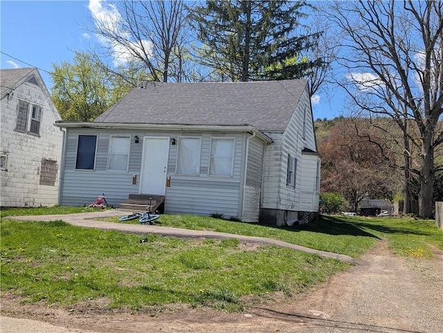 bungalow featuring a front yard, a shingled roof, and entry steps